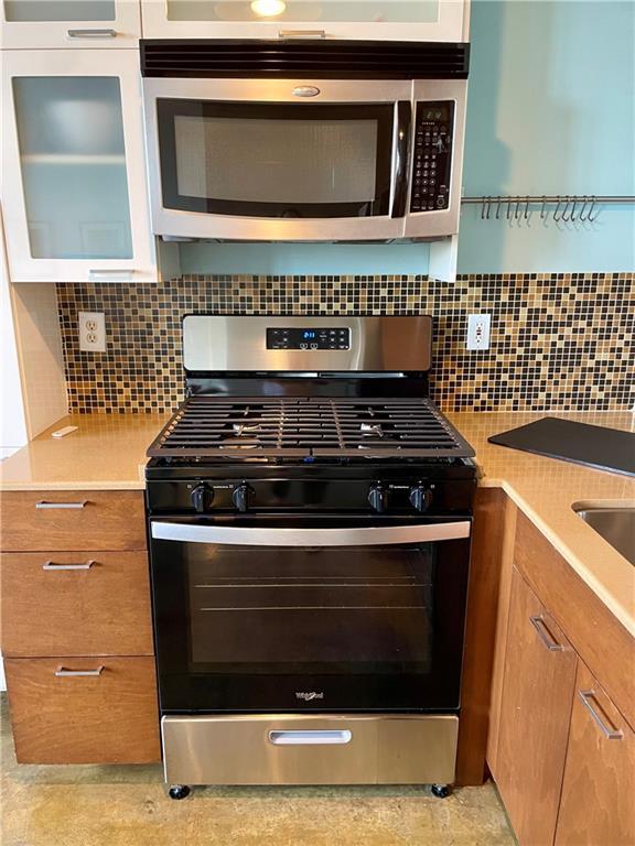 kitchen with brown cabinetry, light countertops, and appliances with stainless steel finishes