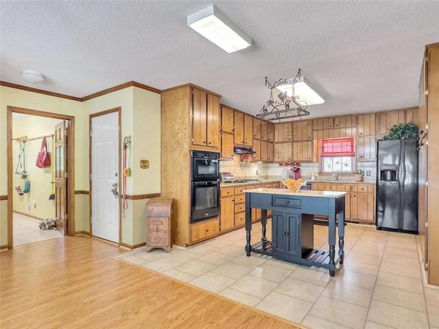 kitchen with light tile patterned flooring, a textured ceiling, black appliances, a breakfast bar, and a center island