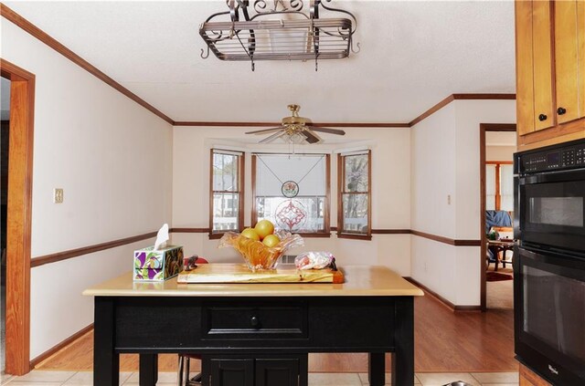 kitchen with ornamental molding, dobule oven black, baseboards, and light wood-type flooring