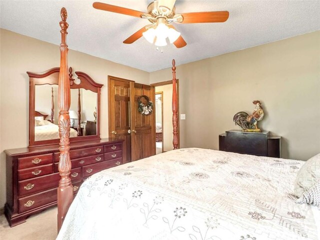 bedroom featuring light carpet, ceiling fan, and a textured ceiling