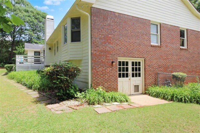 view of side of property featuring brick siding, fence, a chimney, and a yard