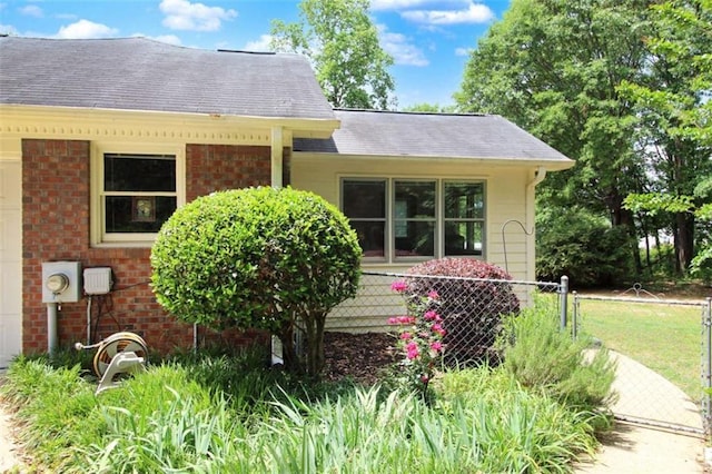 view of front of home with brick siding, fence, and roof with shingles