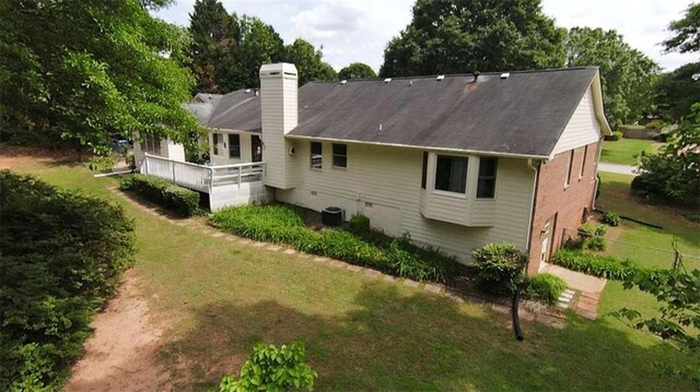 rear view of property featuring a chimney, central AC, and a yard