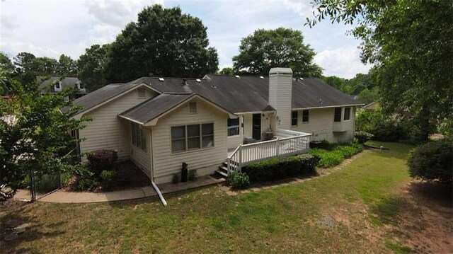 back of house featuring a chimney, a deck, and a yard