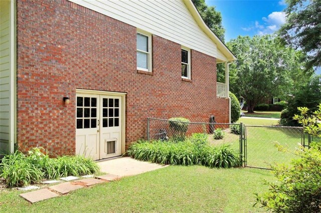 view of side of property with a yard, brick siding, a gate, and fence