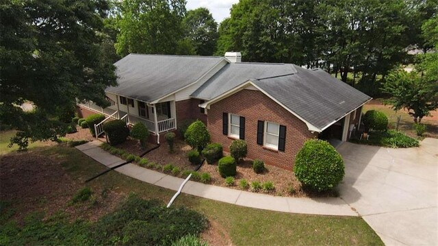 exterior space with brick siding, concrete driveway, and a shingled roof