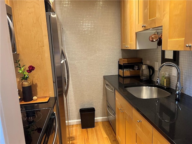 kitchen with black range oven, sink, decorative backsplash, dark stone countertops, and light hardwood / wood-style floors