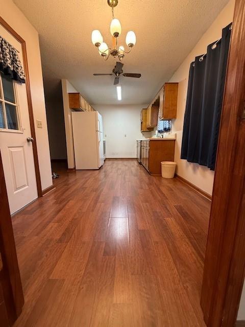 100 Walter Leon Dr, Chatsworth, GA 30705 - kitchen with freestanding refrigerator, brown cabinetry, wood finished floors, ceiling fan, and a chandelier