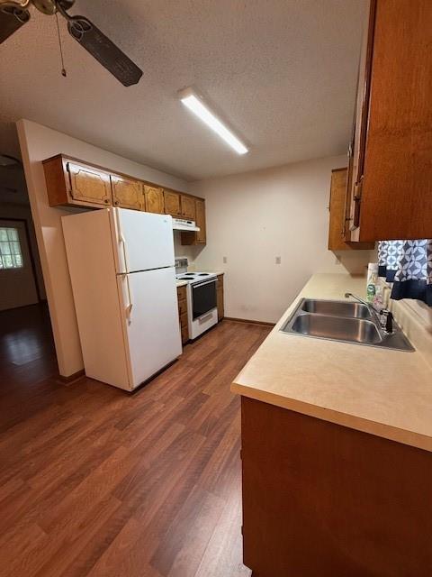100 Walter Leon Dr, Chatsworth, GA 30705 - kitchen with white appliances, brown cabinetry, under cabinet range hood, dark wood finished floors, and ceiling fan
