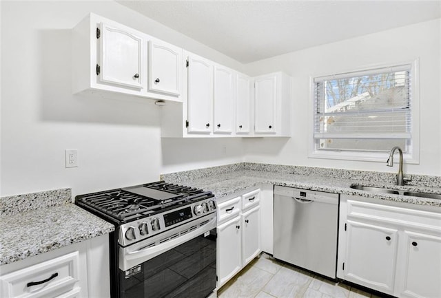 kitchen with white cabinetry, sink, light stone counters, and stainless steel appliances