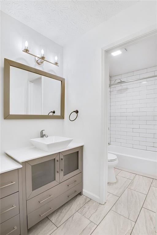 full bathroom with tiled shower / bath, vanity, a textured ceiling, and toilet