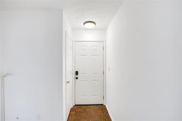 hallway with dark parquet flooring and a textured ceiling