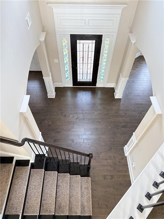 foyer featuring arched walkways, stairway, wood finished floors, and baseboards