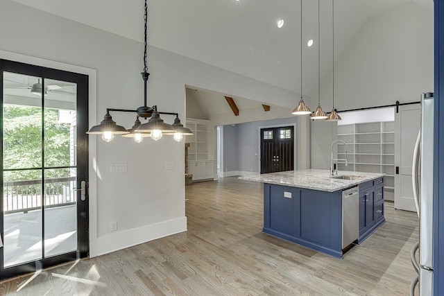 kitchen with blue cabinetry, a barn door, appliances with stainless steel finishes, a sink, and light wood-type flooring