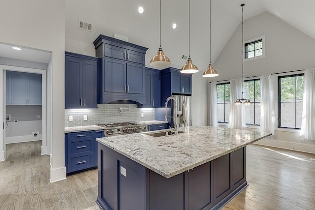 kitchen with visible vents, blue cabinets, a kitchen island with sink, stainless steel appliances, and light wood-style floors