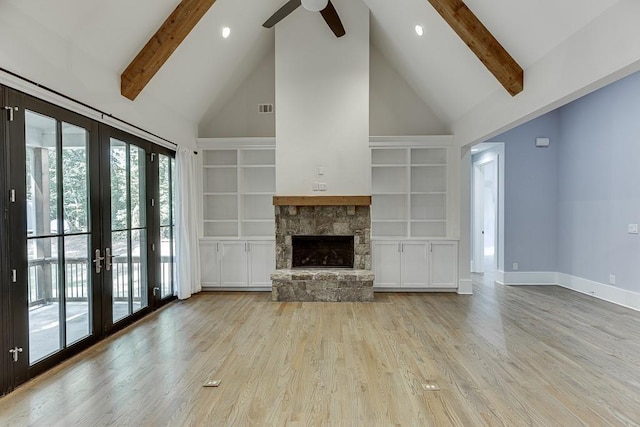 unfurnished living room with visible vents, wood finished floors, beamed ceiling, and a stone fireplace