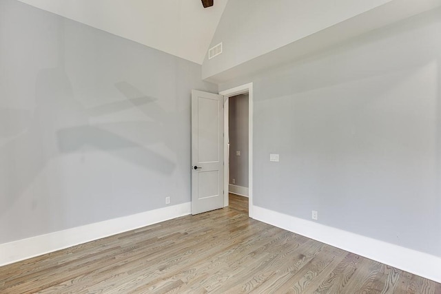 spare room featuring high vaulted ceiling, light wood finished floors, visible vents, and baseboards