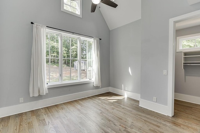 spare room with high vaulted ceiling, a ceiling fan, baseboards, and wood finished floors