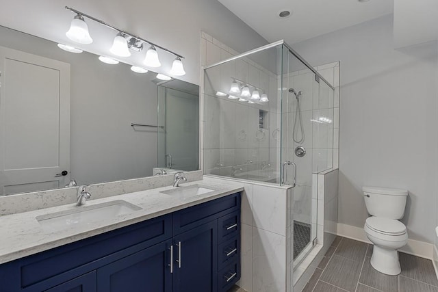 bathroom with double vanity, a stall shower, a sink, and toilet