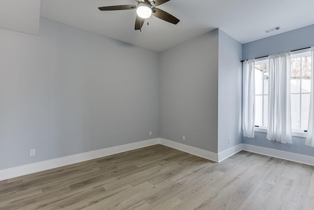 unfurnished room featuring light wood-style floors, visible vents, baseboards, and a ceiling fan