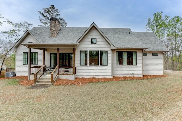 view of front facade featuring a chimney, a shingled roof, covered porch, central AC unit, and ceiling fan