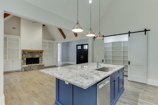 kitchen featuring light wood finished floors, a barn door, dishwasher, blue cabinets, and a sink