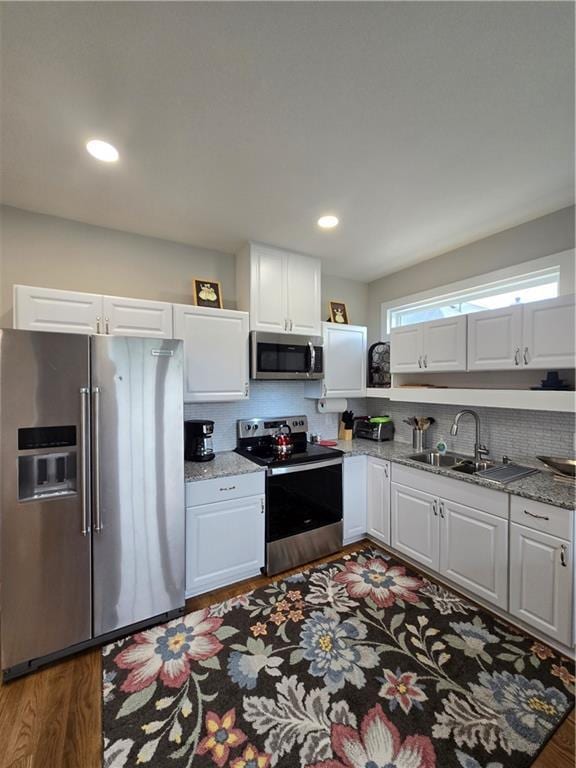 kitchen with white cabinets, light stone countertops, dark wood-type flooring, and appliances with stainless steel finishes