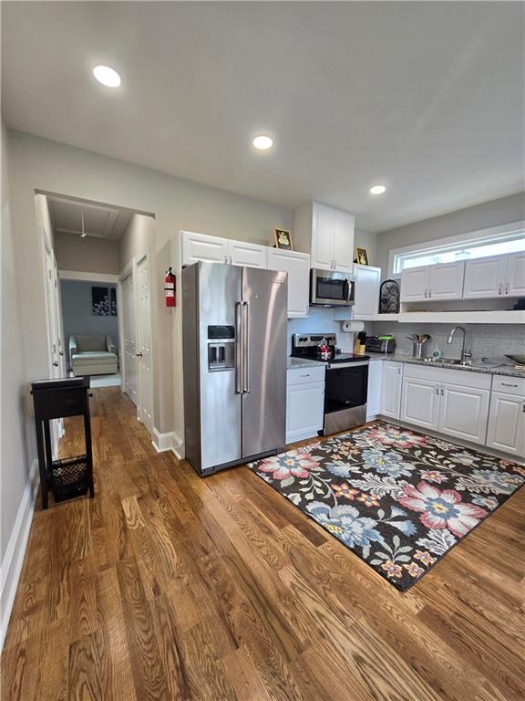 kitchen with white cabinets, stainless steel appliances, and hardwood / wood-style flooring