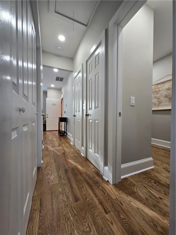 hallway with visible vents, dark wood-type flooring, attic access, and baseboards