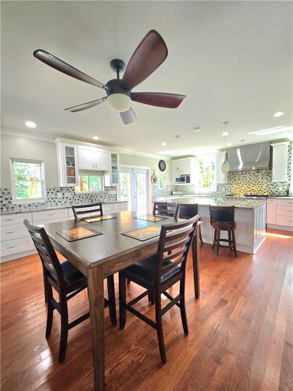 dining area featuring light hardwood / wood-style flooring, a wealth of natural light, ornamental molding, and ceiling fan