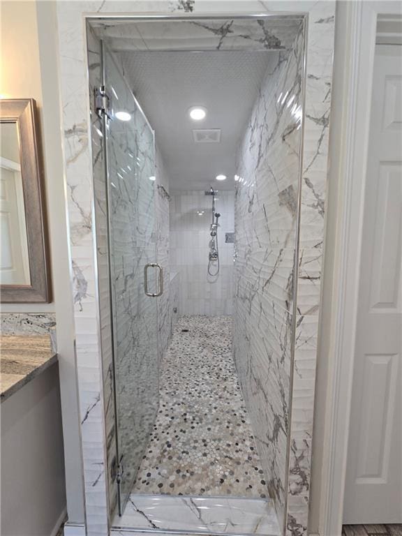 bathroom featuring visible vents, a marble finish shower, and vanity