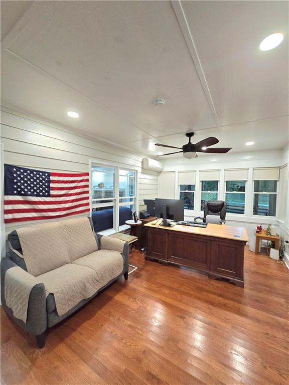 office space featuring an AC wall unit, ceiling fan, and light wood-style flooring