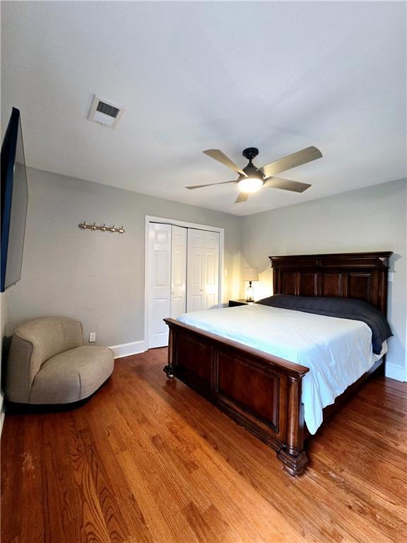 bedroom with ceiling fan, a closet, and wood-type flooring