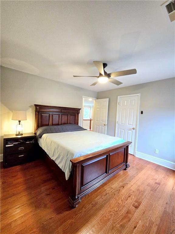 bedroom featuring a ceiling fan, baseboards, visible vents, and wood finished floors