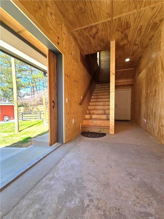 interior space featuring wood ceiling, concrete flooring, and wooden walls