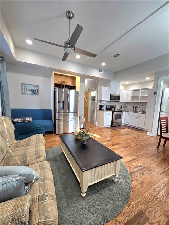 living area featuring light wood-type flooring, visible vents, and recessed lighting