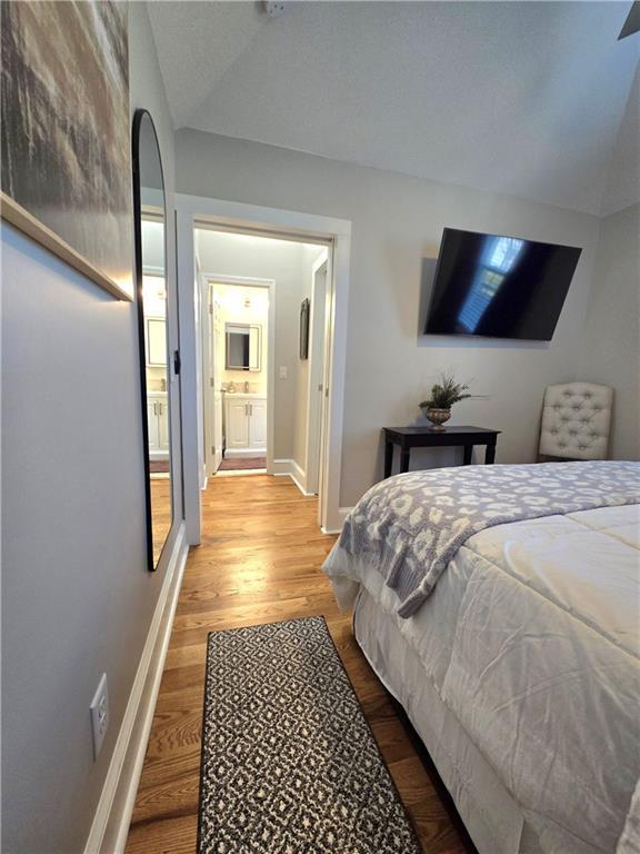 bedroom featuring hardwood / wood-style floors and vaulted ceiling