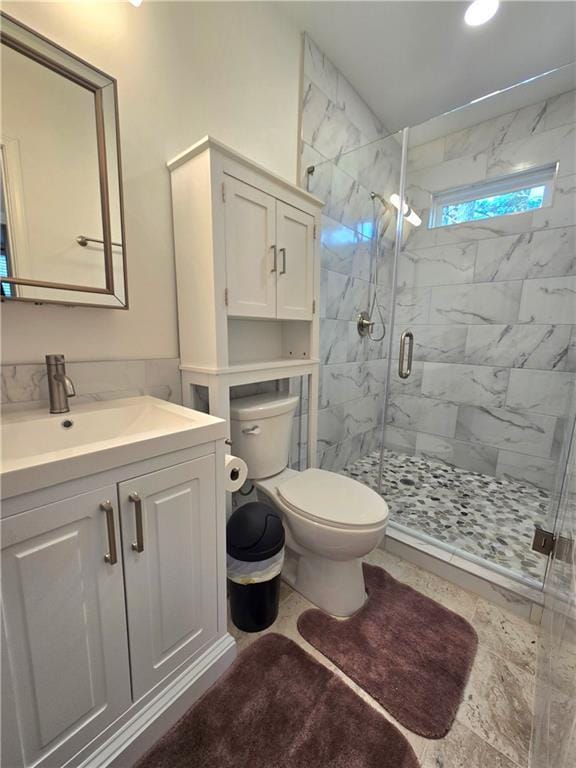 bathroom featuring toilet, a stall shower, and vanity