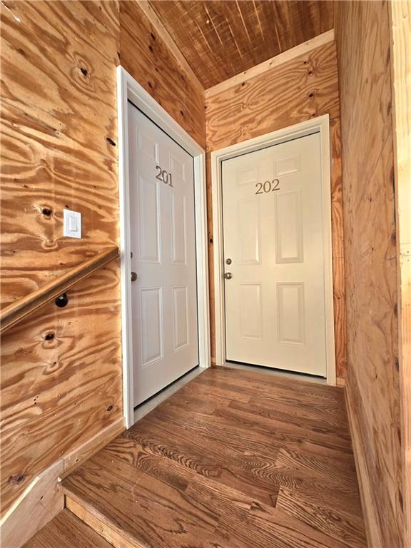 doorway to outside featuring wood ceiling, wooden walls, and wood finished floors