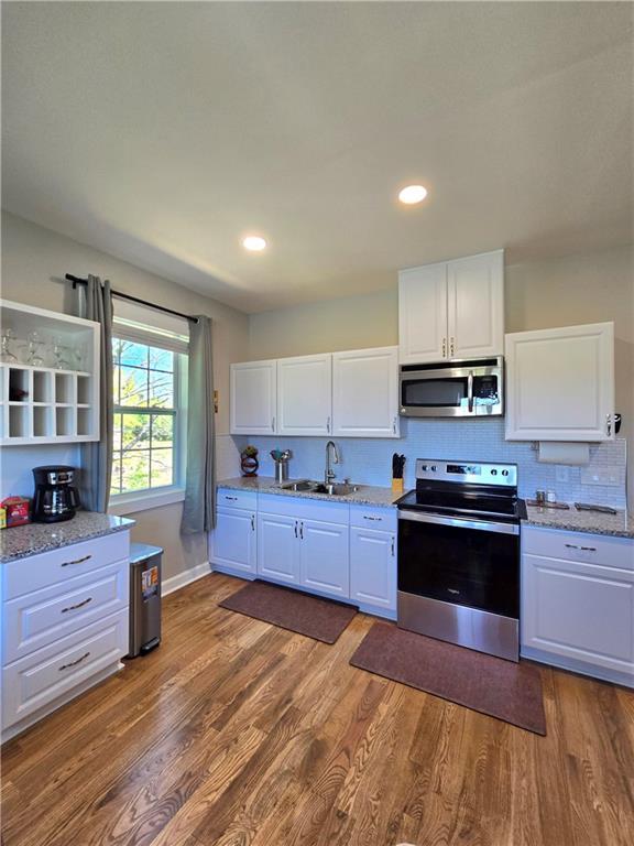 kitchen featuring sink, white cabinets, stainless steel appliances, and wood-type flooring