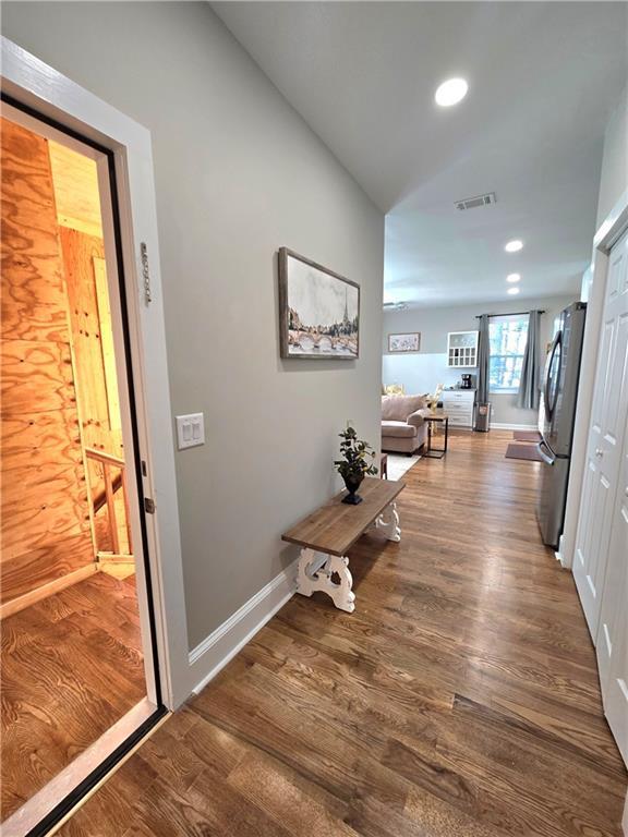 corridor featuring baseboards, visible vents, wood finished floors, vaulted ceiling, and recessed lighting