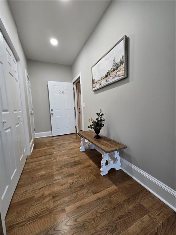 hall with baseboards and dark wood-style flooring