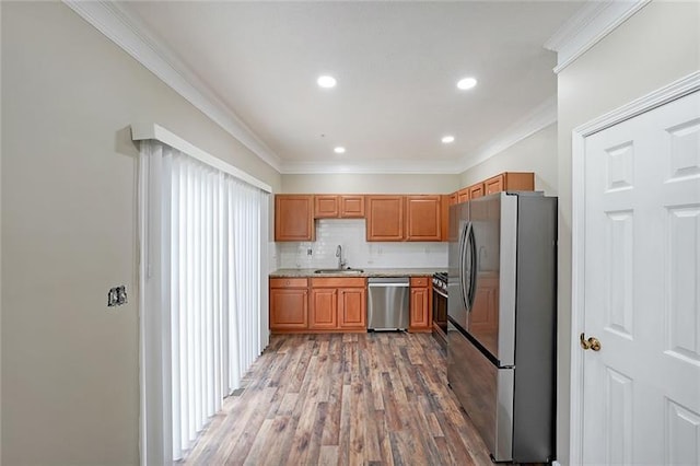 kitchen with sink, crown molding, decorative backsplash, appliances with stainless steel finishes, and light wood-type flooring