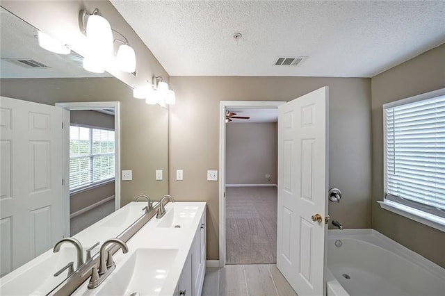 bathroom featuring a bathtub, ceiling fan, a textured ceiling, and vanity