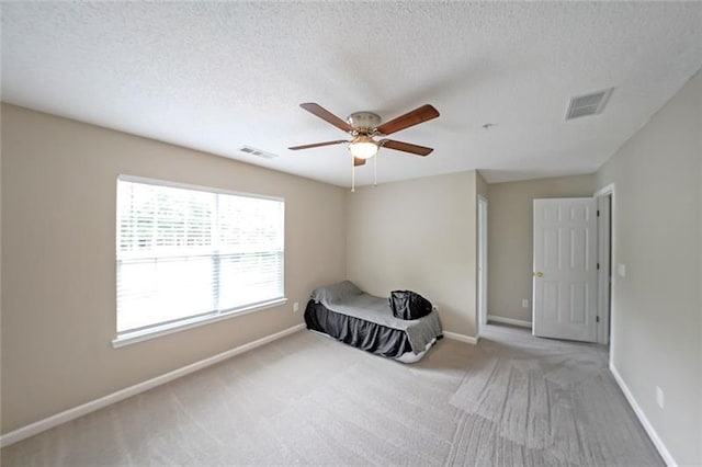 unfurnished bedroom featuring ceiling fan, carpet, and a textured ceiling