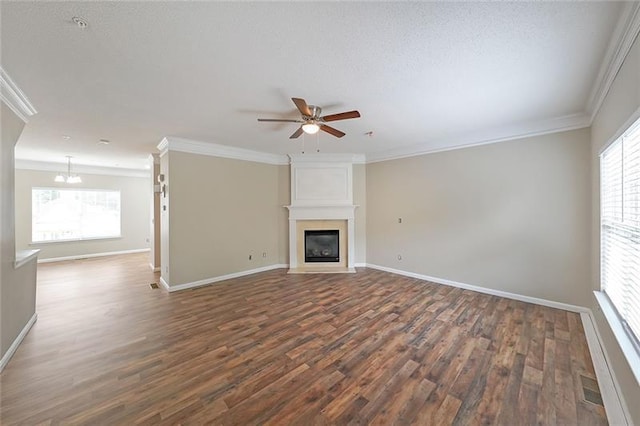 unfurnished living room featuring dark hardwood / wood-style floors, a large fireplace, ornamental molding, and a wealth of natural light