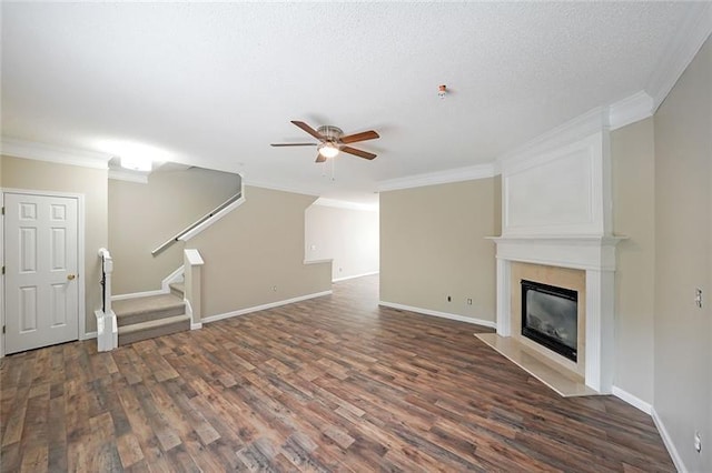 unfurnished living room with a fireplace, dark hardwood / wood-style floors, ceiling fan, and crown molding