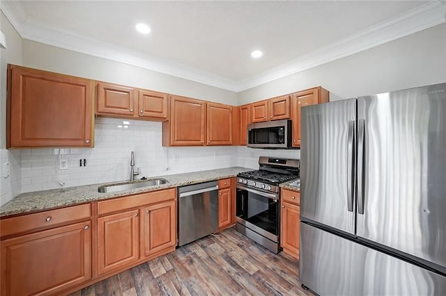 kitchen featuring sink, light stone counters, light hardwood / wood-style flooring, backsplash, and appliances with stainless steel finishes