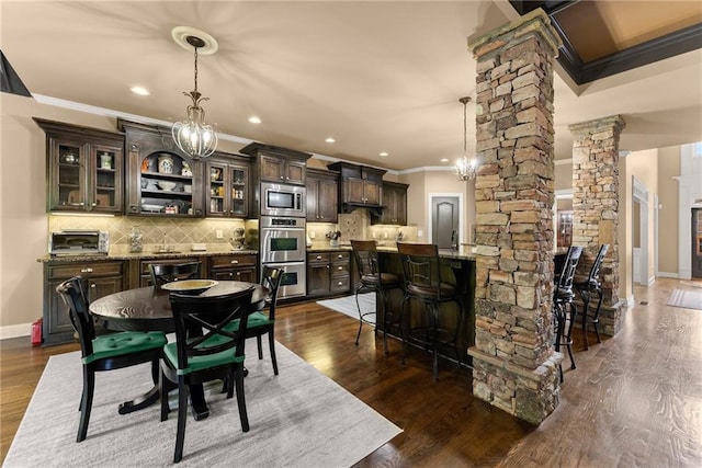 dining space featuring ornate columns, ornamental molding, dark wood-style flooring, and a toaster