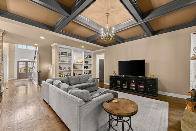 living area with beam ceiling, wood finished floors, baseboards, an inviting chandelier, and coffered ceiling